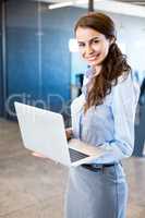 Portrait of young woman using laptop in office