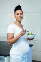 Portrait of pregnant woman holding a bowl of salad