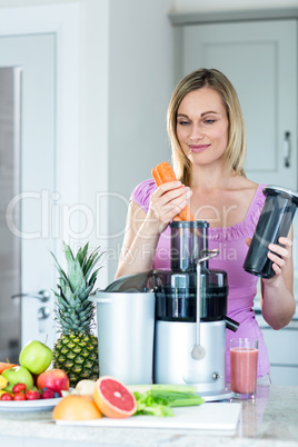 Blonde woman preparing a smoothie in the kitchen