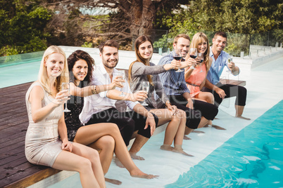 Young people sitting by swimming pool