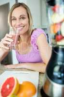 Pretty blonde woman drinking her homemade smoothie