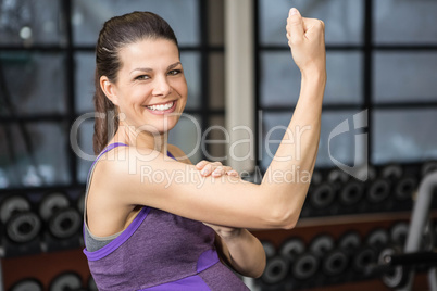 Smiling pregnant woman showing biceps