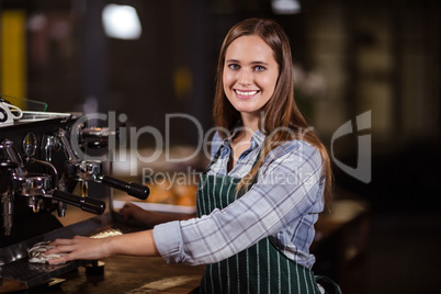 Smiling barista cleaning coffee machine