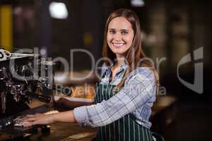 Smiling barista cleaning coffee machine