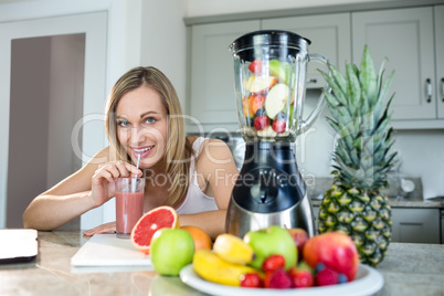 Pretty blonde woman holding her homemade smoothie