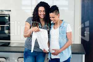 Portrait of lesbian couple looking at babys clothes