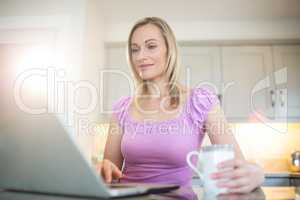 Pretty blonde woman having coffee and using laptop