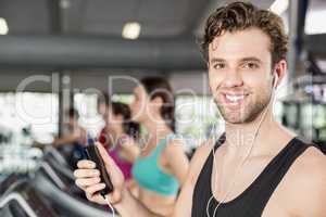 Smiling muscular man on treadmill listening to music