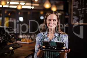 Smiling barista holding tray with coffees
