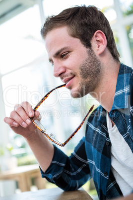 Handsome man working and chewing his glasses