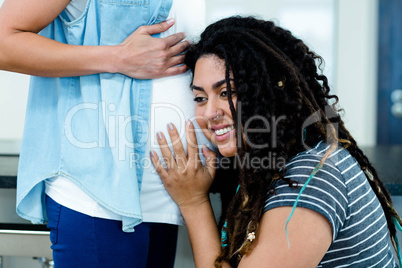 Woman listening to pregnant partners stomach