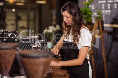 Pretty waitress using the coffee machine