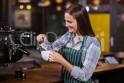 Smiling barista preparing cappuccino