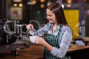 Smiling barista preparing cappuccino