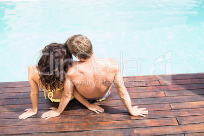 Rear view of young couple sitting by poolside