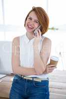 smiling hipster business woman sitting on her desk on the phone