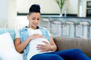 Pregnant woman relaxing on sofa in living room