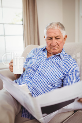 Senior man reading newspaper in living room