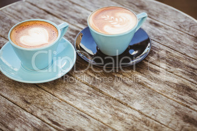 Cup of cappuccino with coffee art on wooden table