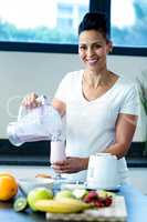 Pregnant woman pouring smoothie in glass