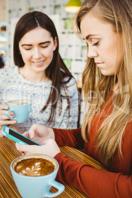 Friends using smartphone and having coffee