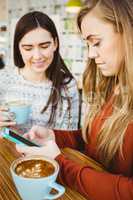 Friends using smartphone and having coffee