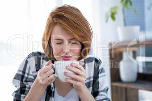smiling hipster woman smelling a cup of coffee