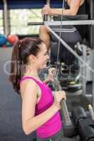 Fit woman using weight machine