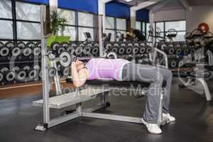 Determined woman lifting barbell