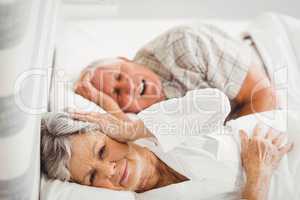 Senior woman covering her ears while man snoring