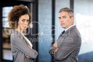 Businessman and businesswoman with arms crossed