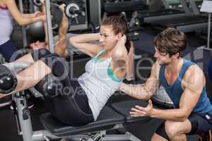 Trainer man helping woman doing her crunches