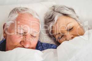 Senior couple sleeping on bed