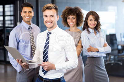 Businessman standing with a laptop and team standing in backgrou