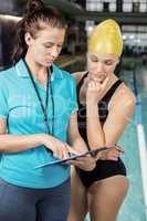 Trainer woman showing clipboard at a swimmer