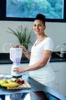 Pregnant woman preparing fruit juice in blender