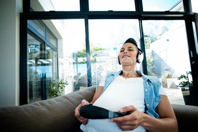 Pregnant woman listening to music on sofa