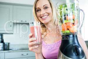Blonde woman drinking a smoothie in the kitchen