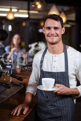 Smiling barista holding cappuccino