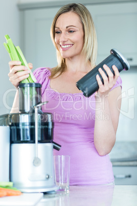 Blonde woman preparing a smoothie in the kitchen