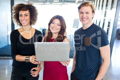 Portrait of colleagues holding laptop and smiling