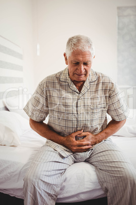 Sick senior man holding stomach