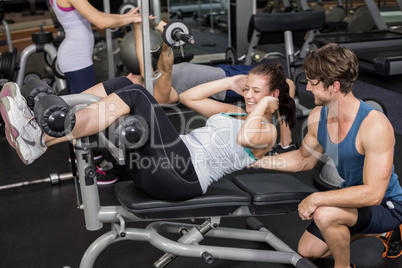 Trainer man helping woman doing her crunches