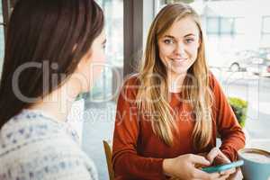 Friends using smartphone and having coffee