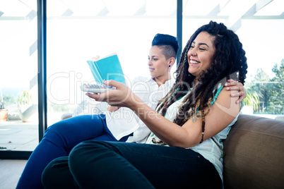 Lesbian couple watching television and reading a book