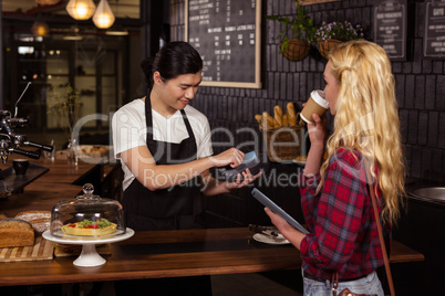 Smiling barista taking credit card from customer