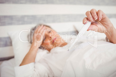 Senior woman checking her temperature