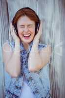 smiling hipster woman listening to loud music through headphones