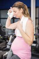 Tired pregnant woman on exercise bike
