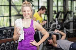 Fit woman posing with athletic woman and man behind